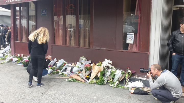 Rue Bichat, des habitants déposent des fleurs devant le bar Le Carillon.&nbsp; (JULIE RASPLUS / FRANCETV INFO)