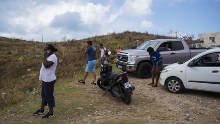 Des habitants de l'île de Saint-Martin tentent de téléphoner, près d'une antenne relais, le 7 septembre 2017. (LIONEL CHAMOISEAU / AFP)