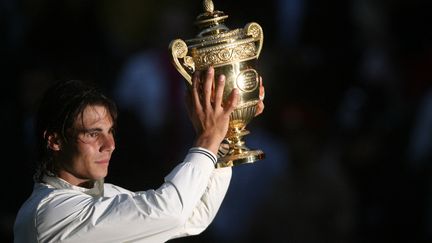 Rafael Nadal soulève son premier titre à Wimbledon, le 6 juillet 2008, après sa victoire en finale contre Roger Federer, une rencontre considéré comme l'une des plus grandes de l'histoire. (LEWIS WHYLD / AFP)