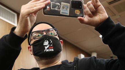 Le cinéaste russe&nbsp;Kirill Serebrennikov tient son smartphone des deux mains dans un tribunal de Moscou, à l'occasion de son audience le 22 juin 2020. Sur son masque, il est écrit "Tsoi est vivant" en hommage au rockeur Viktor Tsoï. (VYACHESLAV PROKOFYEV /TASS / SIPA USA)