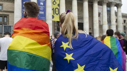 Des manifestants enveloppés dans des drapeaux LGBT et de l'Union européenne, le 30 août 2020 à Varsovie, en Pologne. (ALEKSANDER KALKA / NURPHOTO / NURPHOTO VIA AFP)