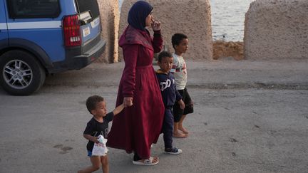 Une famille de migrants, le 18 septembre, sur le port de Lampedusa (ZAKARIA ABDELKAFI / AFP)