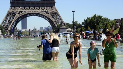 Des gens se rafraîchissent devant la Tour Eiffel, à Paris, le 19 juillet 2016. (BERTRAND GUAY / AFP)