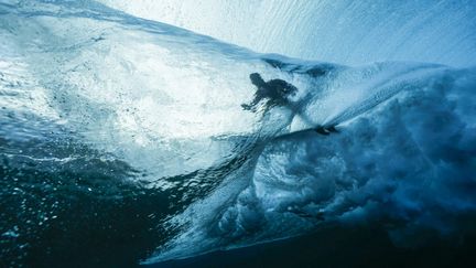 Transparence. A Teahupo'o (Tahiti), le Français Joan Duru dispute le premier tour des qualifications des épreuves de surf, 27 juillet. (BEN THOUARD / AFP)