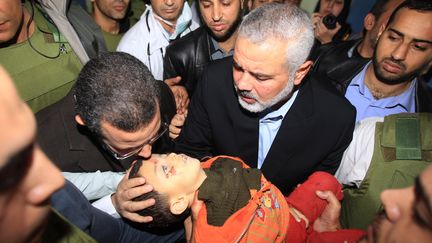 Le leader palestinien de Gaza&nbsp;Isma&iuml;l Haniyeh tend au Premier ministre &eacute;gyptien Hisham Qandil le corps d'un enfant mort &agrave; l'h&ocirc;pital de Gaza. (MAHMUD HAMS / AFP)