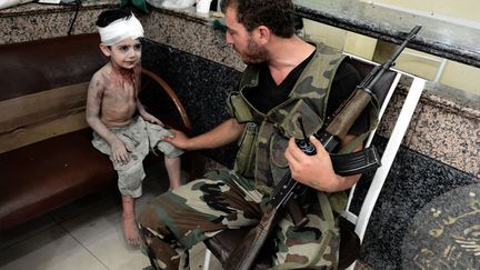 Un membre de l'Arm&eacute;e syrienne libre r&eacute;conforte un jeune gar&ccedil;on bless&eacute; dans un h&ocirc;pital d'Alep (Syrie), le 24 ao&ucirc;t 2012. (ARIS MESSINIS / AFP)