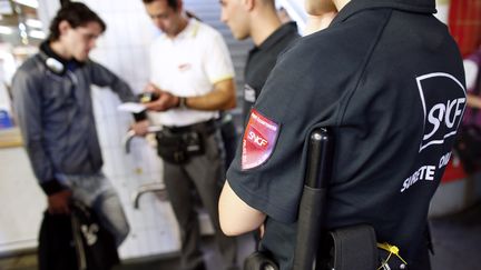 Des policiers en charge de la s&eacute;curit&eacute; du r&eacute;seau SNCF accompagnent un contr&ocirc;leur qui verbalise un voyageur, le 5 juillet 2012 &agrave; Paris. (THOMAS SAMSON / AFP)