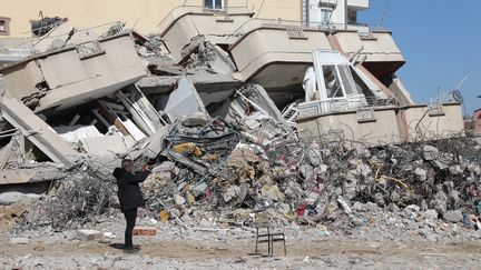 Un homme prend une photo devant des immeubles ravagés par les séismes du 6 février 2023, le 16 février 2023 à Gaziantep (Turquie). (ZEIN AL RIFAI / AFP)