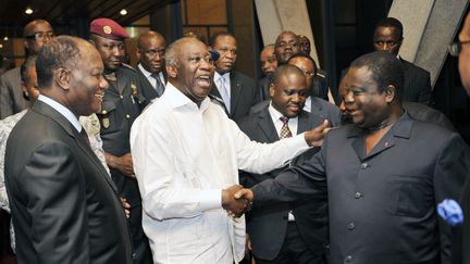 Au centre, Laurent Gbagbo (en blanc) et Henri Konan Bédié échangent une poignée de main au palais présidentiel le 30 juin 2010, à Abidjan (Côte d'Ivoire), sous les yeux d'Alassane Ouattara (à gauche) et en présence de Guillaume Soro (à droite de Laurent Gbagbo).&nbsp; (SIA KAMBOU / AFP)