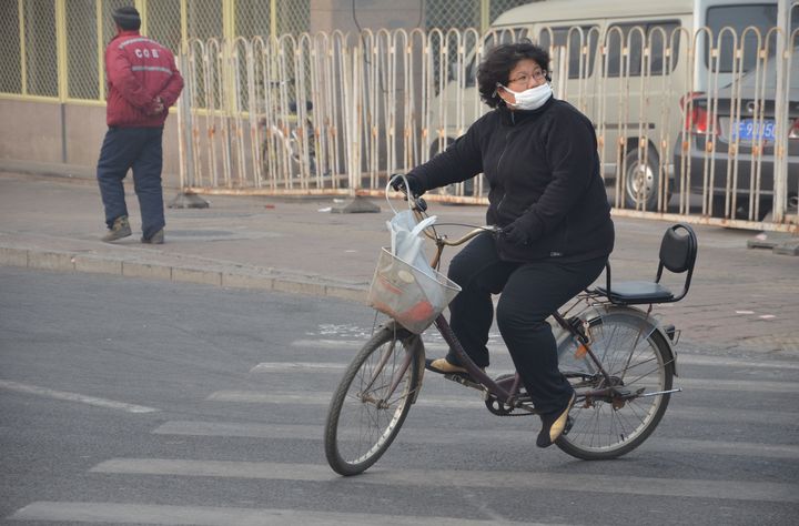 Ce type de masque, en coton, que porte cette cycliste &agrave; P&eacute;kin en janvier 2014, ne prot&egrave;ge absolument pas des particules fines PM2.5. (THOMAS BAIETTO / FRANCETV INFO)