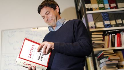 L'&eacute;conomiste fran&ccedil;ais Thomas Piketty pose avec son livre Le Capital au XXIe si&egrave;cle, le 12 mai 2014. ( CHARLES PLATIAU / REUTERS)