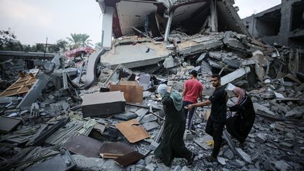 Des habitants de la bande de Gaza dans les décombres, le 24 octobre 2023. (MAJDI FATHI / NURPHOTO / AFP)