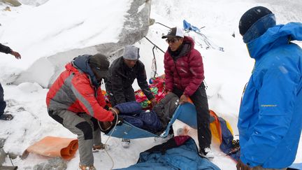 Des secouristes transportent une personne bless&eacute;e au camp de base de l'Everest, samedi 26 avril 2015 (ROBERTO SCHMIDT / AFP)