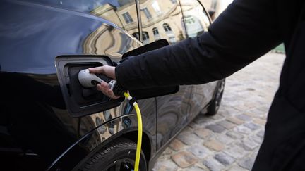 Une personne recharge son véhicule électrique, en octobre 2019 à Paris. (ALEXIS SCIARD / MAXPPP)