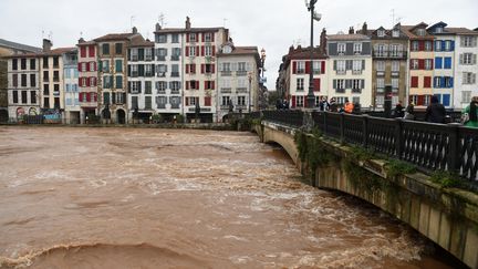Des passants observent la crue de la Nive dans le centre-ville de Bayonne (Pyrénées-Atlantiques), le 10 décembre 2021. (GAIZKA IROZ / AFP)