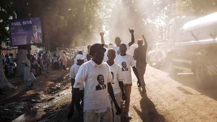 Des partisans du président camerounais Paul Biya marchent dans une rue de la ville, après sa réunion électorale, le 29 septembre 2018. C’était la première fois depuis 2012 que le président se rendait dans une province. Jamais une élection camerounaise n'avait encore été préparée, alors que l'armée est déployée dans trois des dix régions du pays: l'extrême-Nord, où elle combat les djihadistes de Boko Haram, et les deux régions anglophones du Nord-Ouest et du Sud-Ouest, où des séparatistes armés réclament l'indépendance. Huit candidats espèrent renverser par les urnes celui qu'on appelle au Cameroun le «Sphinx». Contrairement aux trois dernières élections où l'opposant de toujours, Ni John Fru Ndi, était le principal challenger, le scrutin semble en 2018 plus ouvert. «C'est la première fois dans l'histoire du Cameroun qu'il y a des candidats d'opposition aussi démarqués, qui ont de vraies offres politiques chacune différente», estime Fred Eboko, politologue camerounais à l'Institut de recherche et développement. Paul Biya est à la tête de l'Etat camerounais depuis 1982. (ALEXIS HUGUET / AFP)