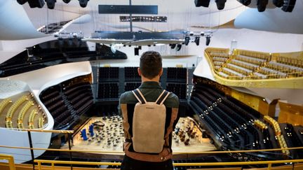 Le producteur de disques français Damien Quintard pose, le 11 mai 2023, à la Philharmonie de Paris, avec un sac à dos vibrant permettant aux personnes sourdes ou malentendantes de profiter des concerts. (BERTRAND GUAY / AFP)