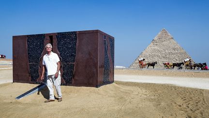 Le cube du britannique Stephen Cox (sur la photo) est un hommage à la pyramide de Khéphren. Il a été réalisé en granit d'Assouan, la même pierre utilisée pour le sarcophage retrouvé à l'intérieur de la chambre funéraire. (ZIAD AHMED / NURPHOTO / AFP)