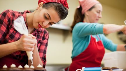 Deux amies pr&eacute;parent des cupcakes lors d'un atelier pratique dans une boulangerie aux Etats-Unis, le 25 janvier 2012, une p&acirc;tisserie devenue tr&egrave;s &agrave; la mode. (RAPHYE ALEXIS / AFP)