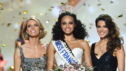 Alicia Aylies, Miss Guyane, devenue Miss France 2017, entourée de Sylvie Tellier, organisatrice, et d'Iris Mittenaere, Miss France 2016, le 17 décembre 2016 à Montpellier. (PASCAL GUYOT / AFP)