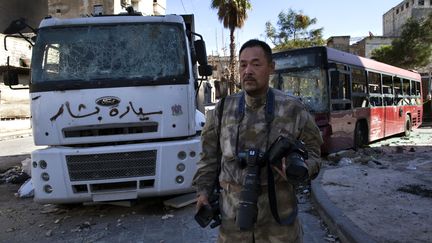 Toshifumi Fujimoto pose avec ses appareils dans la vieille ville ravag&eacute;e d'Alep (Syrie), le 27 d&eacute;cembre 2012. (AFP)