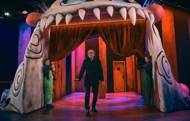 Le réalisateur et scénariste américain Tim Burton dans la gueule d'un de ses monstres, qui constitue l'entrée de son exposition-Labyrinthe. (BENOIT DURAND / HANS LUCAS / AFP)