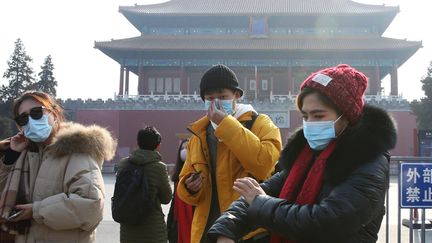 Des personnes avec des masques le 25 janvier 2020, devant la Cité interdite, à Pékin (Chine), fermée pour éviter la propagation du coronavirus. (KOKI KATAOKA / YOMIURI / AFP)