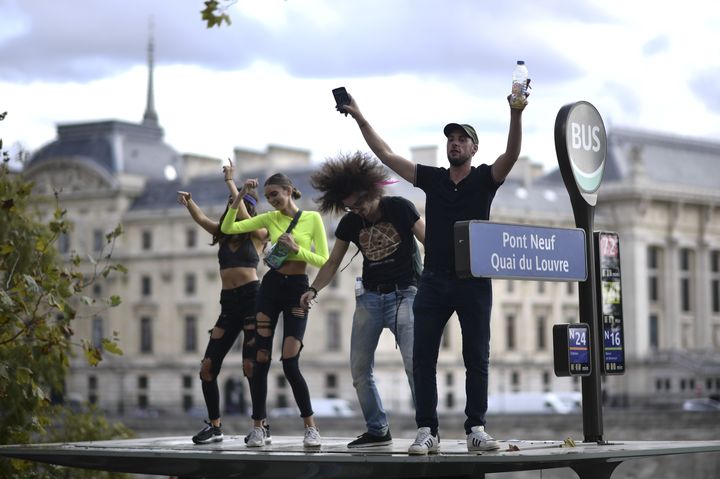 De jeunes "teufeurs" se déchaînent sur le toit d'un abri-bus au passage des chars de la 21e Techno Parade, samedi 28 septembre 2019 à Paris. (MARTIN BUREAU / AFP)