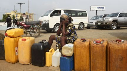 Une femme prend son mal en patience en cette fin décembre 2017. Sur l'origine de la crise, chacun se renvoie la balle. Certains distributeurs accusent la Société nationale nigériane du pétrole de ne pas mettre assez de ressources pour faire face à une demande accrue pour les fêtes de fin d'année. Maikanti Baru, son directeur, met en cause les vendeurs d'essence à la sauvette qui, selon lui, paralysent les stations-service pour faire monter les prix de vente au marché noir. De leur côté, les Nigérians suspectent le gouvernement de générer cette crise pour pouvoir augmenter les prix du carburant en 2018. De quoi alimenter les tensions dans ce pays de 190 millions d'habitants. (PIUS UTOMI EKPEI / AFP)