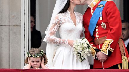 Le prince britannique William et son épouse Catherine, duchesse de Cambridge, s'embrassent sur le balcon du palais de Buckingham, à Londres (Royaume-Uni) le 29 avril 2011.&nbsp;Le regard agacé de Grace van Cutsem (à gauche), demoiselle d'honneur lors du mariage, avait provoqué l'hilarité des spectateurs et rendu ce cliché célèbre. (LEON NEAL / AFP)