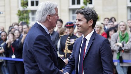 Le nouveau Premier ministre, Michel Barnier, serre la main du chef du gouvernement sortant, Gabriel Attal, lors de la cérémonie de passation de pouvoirs à l'hôtel Matignon, à Paris, le 5 septembre 2024. (STEPHANE DE SAKUTIN / AFP)