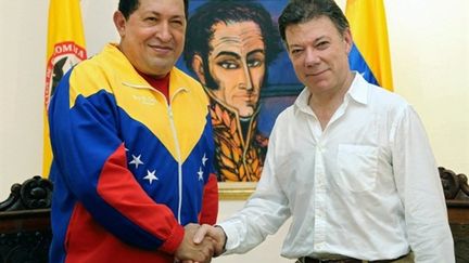 Hugo Chavez (à gauche) et Juan Manuel Santos (à droite) se serrant la main sous le portrait de Bolivar le 10 août 2010 (AFP - Felipe Pinzon)