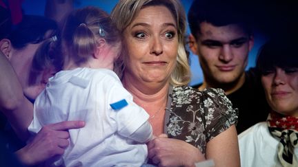 La candidate du Front national &agrave; l'&eacute;lection pr&eacute;sidentielle Marine Le Pen grimace en portant une petite fille lors de son meeting &agrave; Bouguenais (Loire-Atlantique), le 25 mars 2012. (MARTIN BUREAU / AFP)