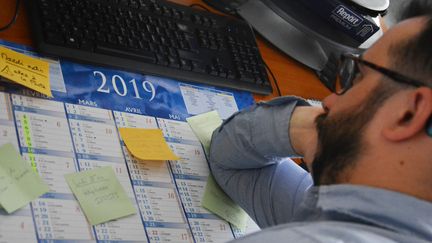 Un homme procrastine au bureau avec un calendrier et ses rendez-vous sous son coude. (JEAN-CHRISTOPHE BOURDILLAT / RADIO FRANCE)