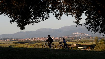 Des Italiens se baladent à vélo dans un parc à Rome, le 4 mai 2020, premier jour où les promenades sont autorisées et les parcs ouverts depuis le début du confinement. (REMO CASILLI / REUTERS)