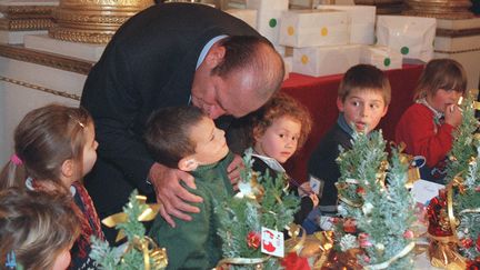 Jacques Chirac embrasse un enfant du personnel de la pr&eacute;sidence de l'Elys&eacute;e, le 17 d&eacute;cembre 1997.&nbsp; (PASCAL GUYOT / AFP POOL / AFP)