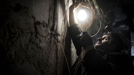 Un civil ukrainien tente d'alimenter en électricité son logement à Lyman, dans la région de Donetsk, le 27 novembre 2022. (METIN AKTAS / ANADOLU AGENCY / AFP)