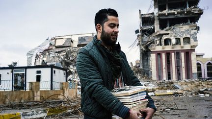 A 21 ans, Abdesatar al-Hamdany apprend la pharmacie. Livres en main, il passe devant les bâtiments détruits de l'université de Mossoul. Les étudiants ne devraient pas y revenir rapidement, car le campus reste source de danger. Des bâtiments sont minés et des substances chimiques sont stockées dans certaines parties du site. (Dimitar DILKOFF / AFP )