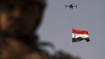 Le drapeau irakien flotte dans les airs, suspendu à un drone de la police fédérale irakienne, pendant que les forces irakiennes célèbrent la libération de Mossoul, le 9 juillet 2017. La reprise de Mossoul est&nbsp;un revers majeur infligé&nbsp;aux djihadistes dans la région. (FADEL SENNA / AFP)