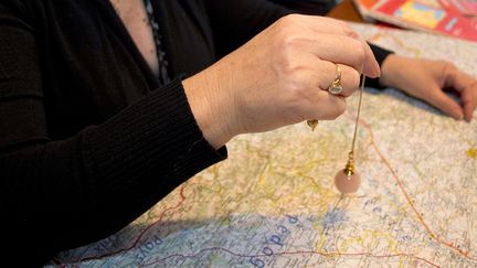 Une cartomancienne utilise un pendule au dessus d'une carte de France le 22 décembre 2011 au Vernet (Haute-Garonne). (PASCAL PAVANI / AFP)