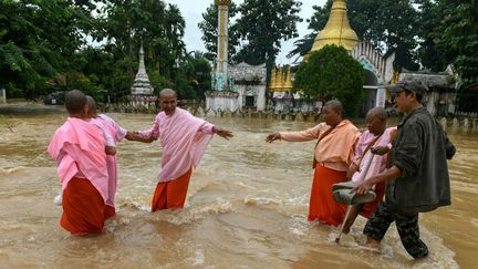 Des moines bouddhistes traversent une route inondée, en Birmanie, le 14 septembre 2024. (SAI AUNG MAIN / AFP)