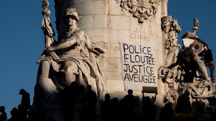 Une banderole visible sur la statue "Le Triomphe de la République", place de la République à Paris, le 28 novembre 2020, lors d'une manifestation contre le projet de loi sur la "sécurité globale". (JOEL SAGET / AFP)