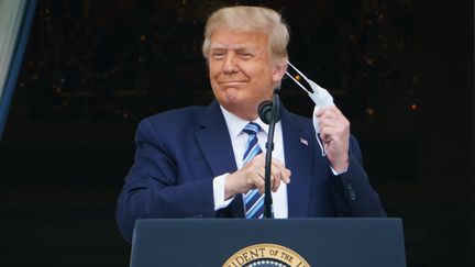 Le président des Etats-Unis, Donald Trump, enlève son masque, le 10 octobre 2020, au balcon de la Maison Blanche, à Washington. (MANDEL NGAN / AFP)