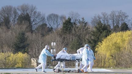 Le personnel médical transporte un patient sur un brancard vers un hélicoptère médicalisé à l'hôpital Emile-Muller de Mulhouse (Haut-Rhin),&nbsp;mardi le 17 mars 2020. (SEBASTIEN BOZON / AFP)