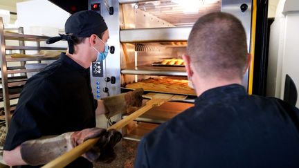 Un apprenti sort des baguettes d'un four de boulangerie, le 21 avril 2021, à Landrethun-le-Nord (Nord). (JOHAN BEN AZZOUZ / LA VOIX DU NORD / MAXPPP)