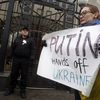 Une manifestante brandit une pancarte indiquant "Poutine, &ocirc;te tes mains de l'Ukraine", devant l'ambassade russe &agrave; Kiev, le 1er mars 2014. (YURY KIRNICHNY / AFP)