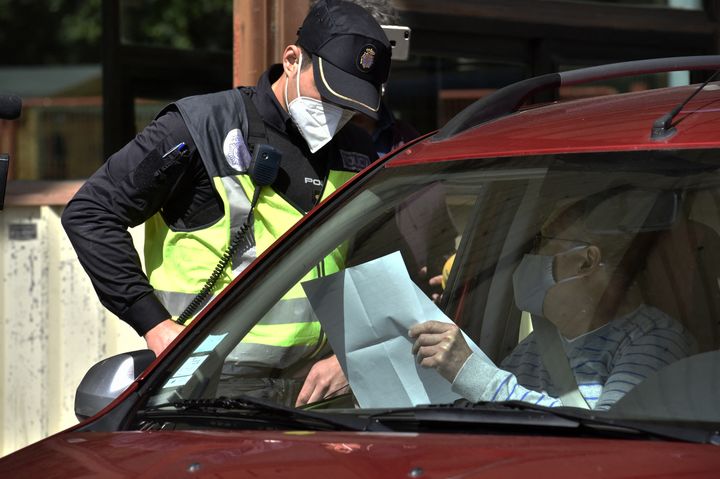 A Spanish police officer checks a PCR test document of a motorist at the Perthus border post (Pyrénées-Orientales), 30 March 2021. (RAYMOND ROIG / AFP)