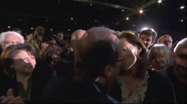 Le candidat socialiste Fran&ccedil;ois Hollande embrasse furtivement sa compagne, la journaliste&nbsp;Val&eacute;rie Trierweiler, &agrave; la fin de son discours de campagne au Bourget (Seine-Saint-Denis), le 22 janvier 2012. (POOL TV / AFP)