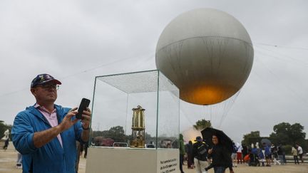 Un visiteur prend une photo près de la vasque montgolfière qui reçoit la flamme olympique, au Jardin des Tuileries lors des JO de Paris 2024. (GEOFFROY VAN DER HASSELT / AFP)