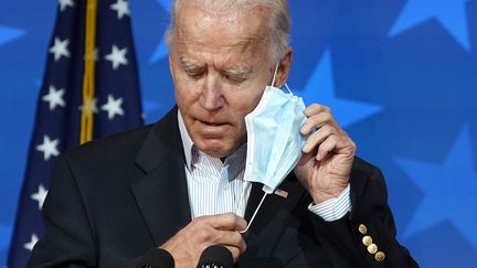 Le candidat démocrate à la présidentielle américaine, Joe Biden, enlève son masque avant de s'exprimer lors d'une conférence de presse, à Wilmington, dans le Delaware, jeudi 5 novembre 2020.&nbsp; (DREW ANGERER / GETTY IMAGES NORTH AMERICA / AFP)